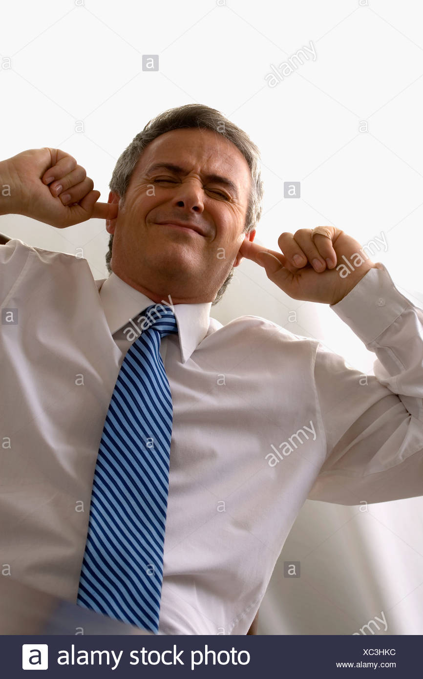 businessman-sitting-at-a-desk-and-putting-his-fingers-in-his-ears-XC3HKC.jpg