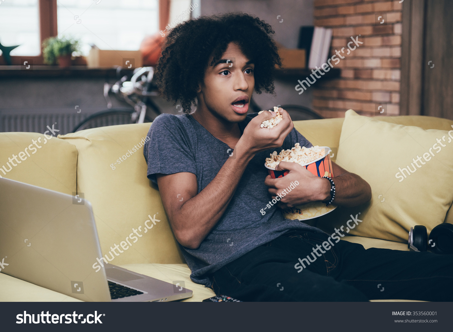 stock-photo-exciting-tv-show-young-african-man-watching-tv-and-keeping-his-mouth-open-while-si...jpg