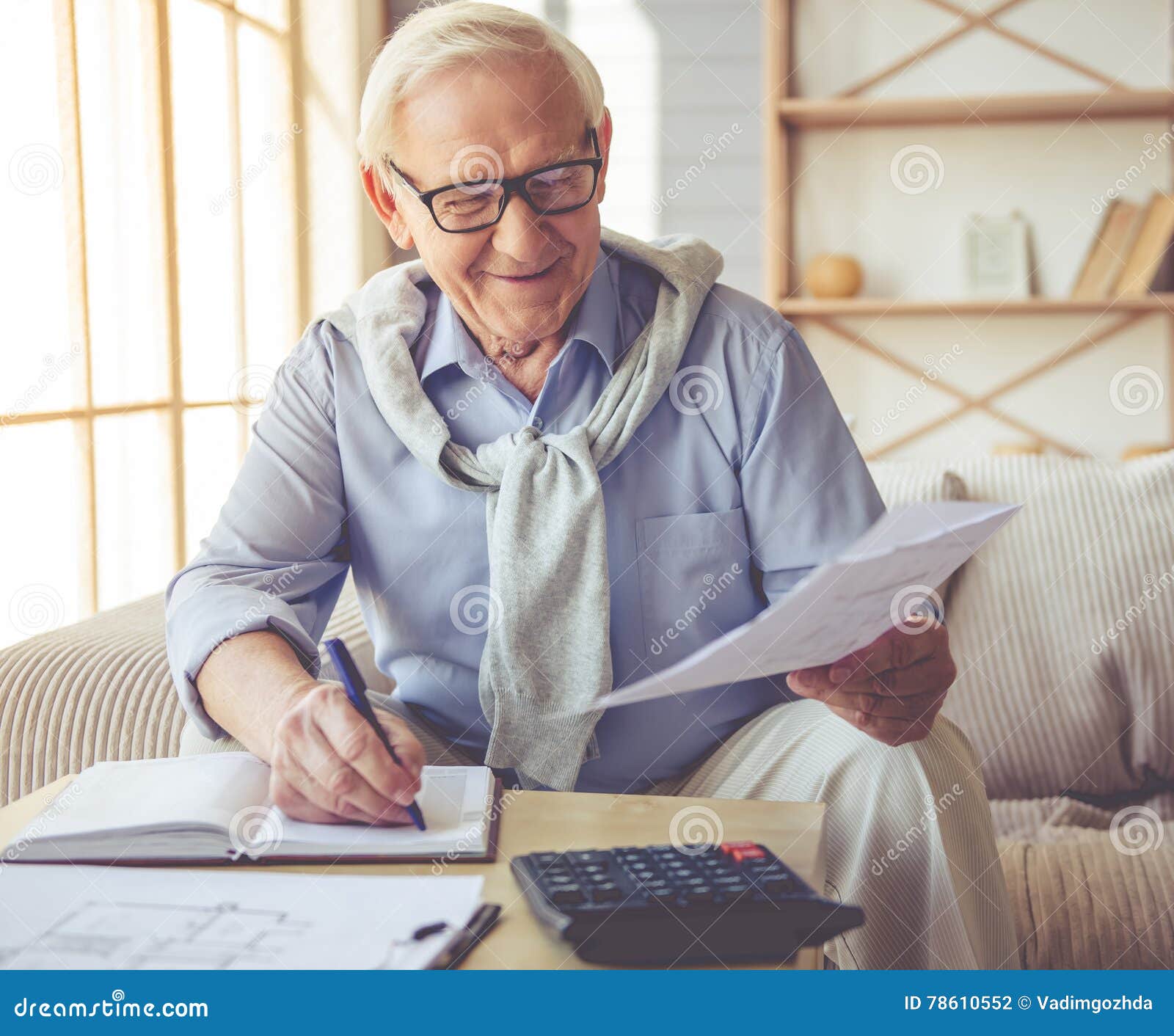handsome-old-man-home-eyeglasses-studying-documents-writing-his-notebook-smiling-working-78610552.jpg
